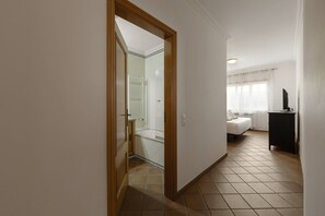 Et hotelværelse med seng, skrivebord og badeværelse med bruser og toilet.