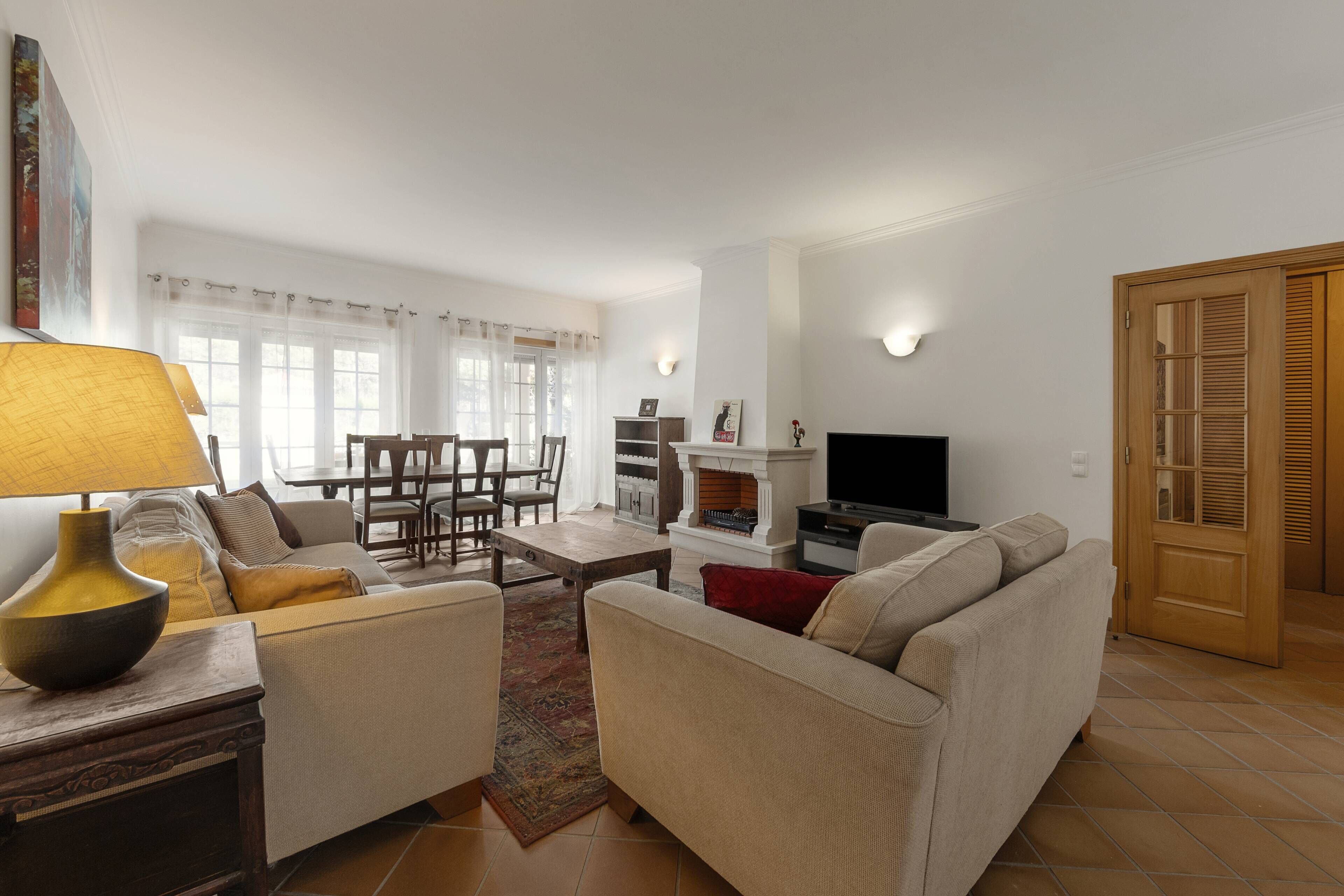 Un salon avec un canapé, une table basse, un téléviseur et une cheminée.