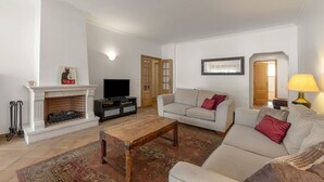 Ett vardagsrum med en öppen spis, en tv, en soffa och ett soffbord.