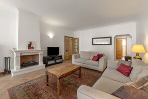 A living room with a fireplace, television, sofa, and a coffee table. - Destino Praia D'El Rei - Shared Pool (Óbidos)