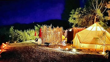 Un terrain de camping avec une tente, une chaise et une petite table.