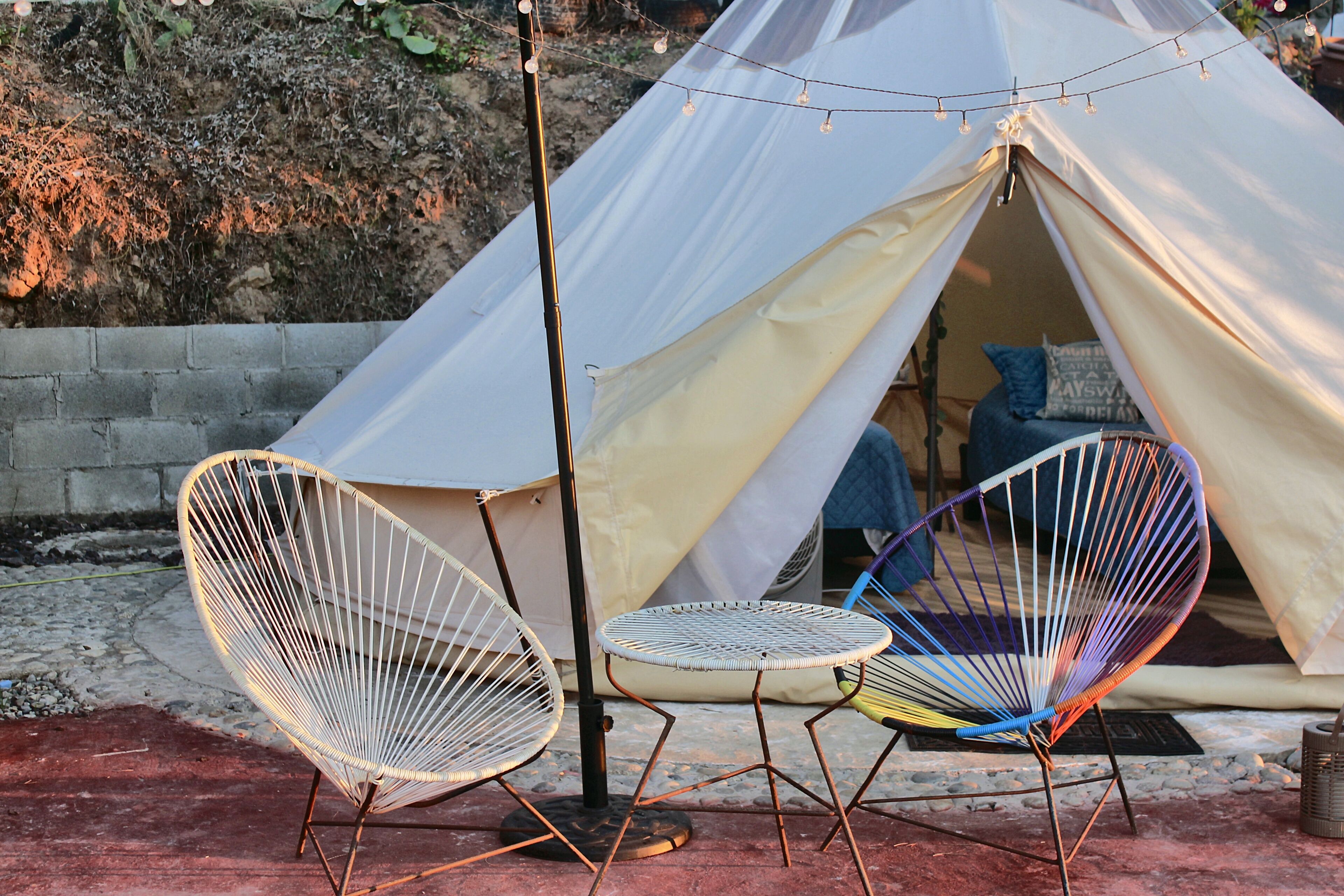 Tienda con un toldo blanco y un conjunto de mesa y silla al frente.