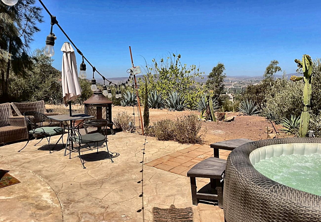 Une terrasse extérieure aménagée avec des meubles en osier, un jacuzzi et une vue sur le paysage désertique.