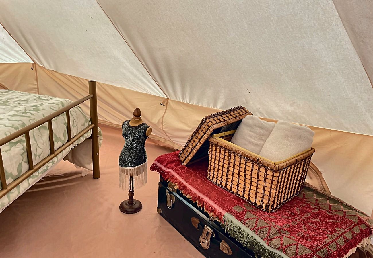 A tent with a bed, a mannequin, and a chest of drawers with a red cloth.