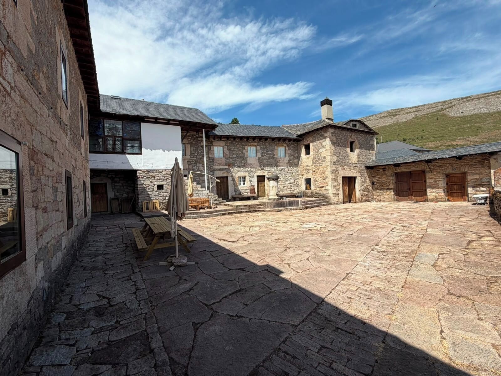 A courtyard with stone flooring, stone buildings, and a large banner.