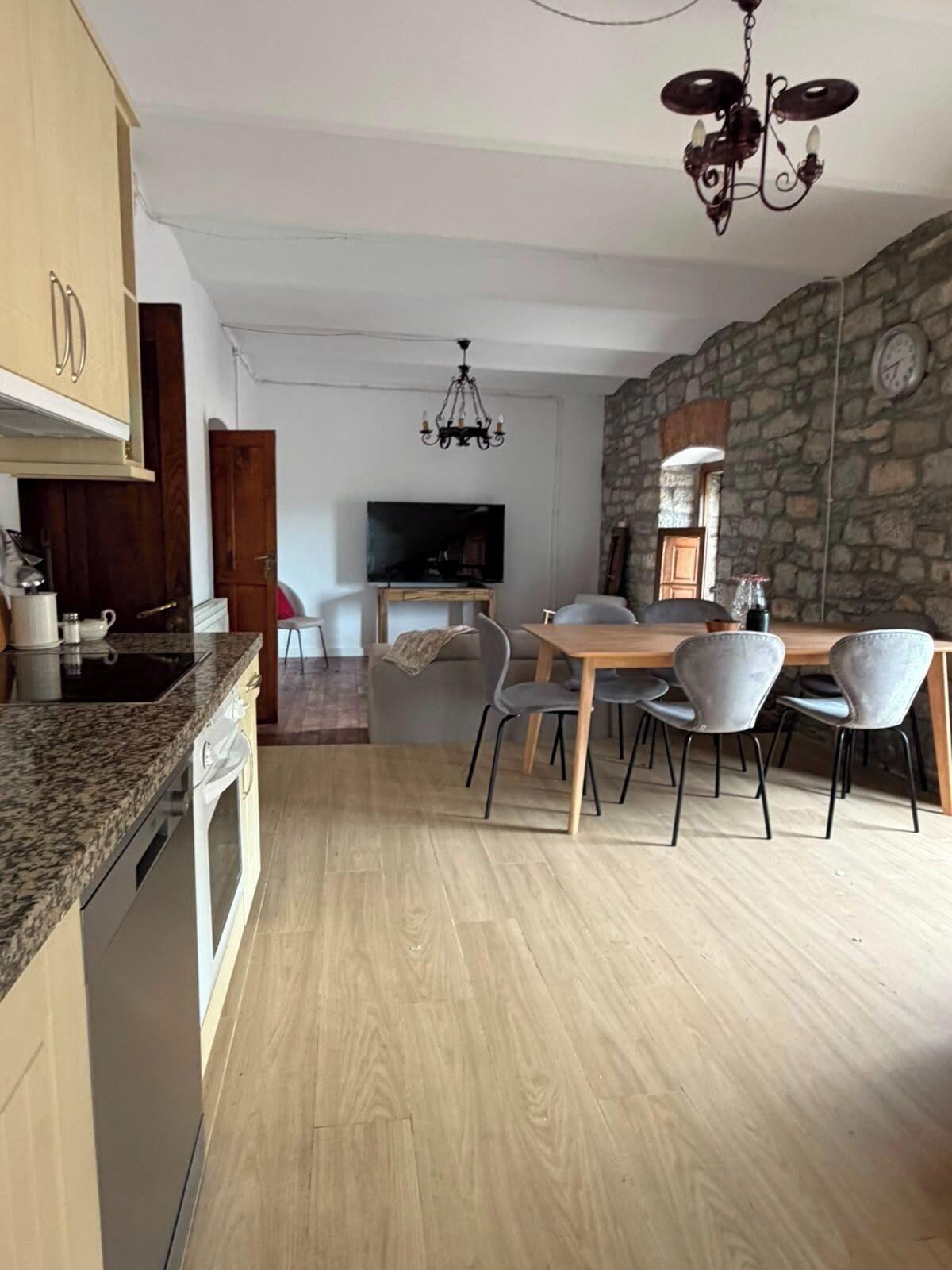 Una cocina moderna con encimeras de granito, un comedor con pared de piedra y una araña.