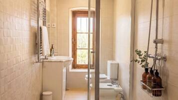 A narrow bathroom with a shower, a toilet, and a sink.