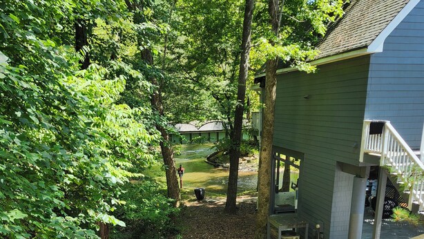 A residential property with a covered outdoor seating area, a visible staircase, and a yard with a small water feature.