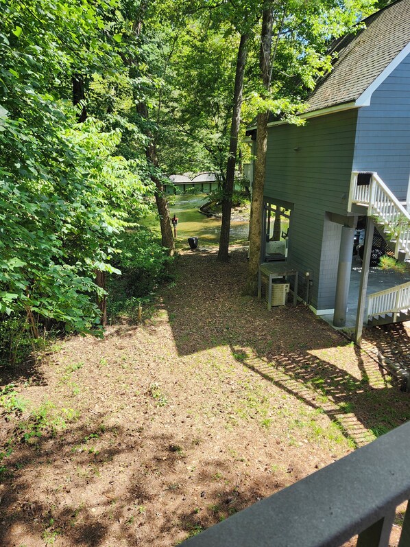 A residential property with a covered outdoor seating area, a visible staircase, and a yard with a small water feature.
