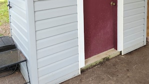 A house with a red door, white trim, and a small porch with a metal table.