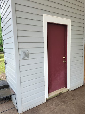 A house with a red door, white trim, and a small porch with a metal table.