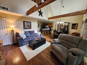 A spacious living room with a fireplace, a dining area, and a kitchen in the background.
