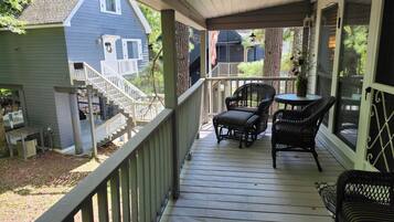 A covered porch with a wooden deck, a staircase, and outdoor furniture.