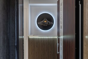 A reception area with a circular sign reading 'WELCOME INN NAPOLI ROOM' and a vertical sign saying 'WELCOME'. - Welcome to the Naples Room (Napoli)