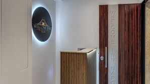 Ein Empfangsbereich mit einem runden Schild, das 'Welcome In Napoli Room' zeigt, und einem vertikalen Schild mit der Aufschrift 'WELCOME IN NAPOLI' auf einer Holzplatte.