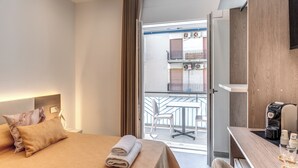 Ein Hotelzimmer mit Bett, Tisch, einer Kaffeemaschine und Blick auf den Außenbalkon.