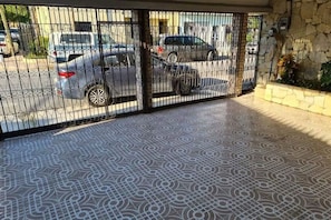 A gated entrance with a patterned floor leading to a parking area.