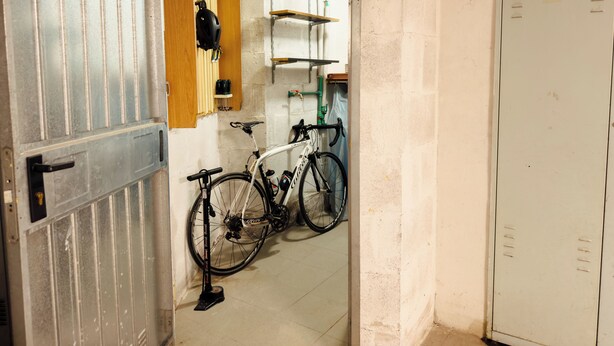 Una porta que dona a una habitació amb una bicicleta i una estant plena d'eines.