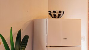 Una cuina amb un frigorífic blanc, una cistella teixida a la part superior i una planta verda.
