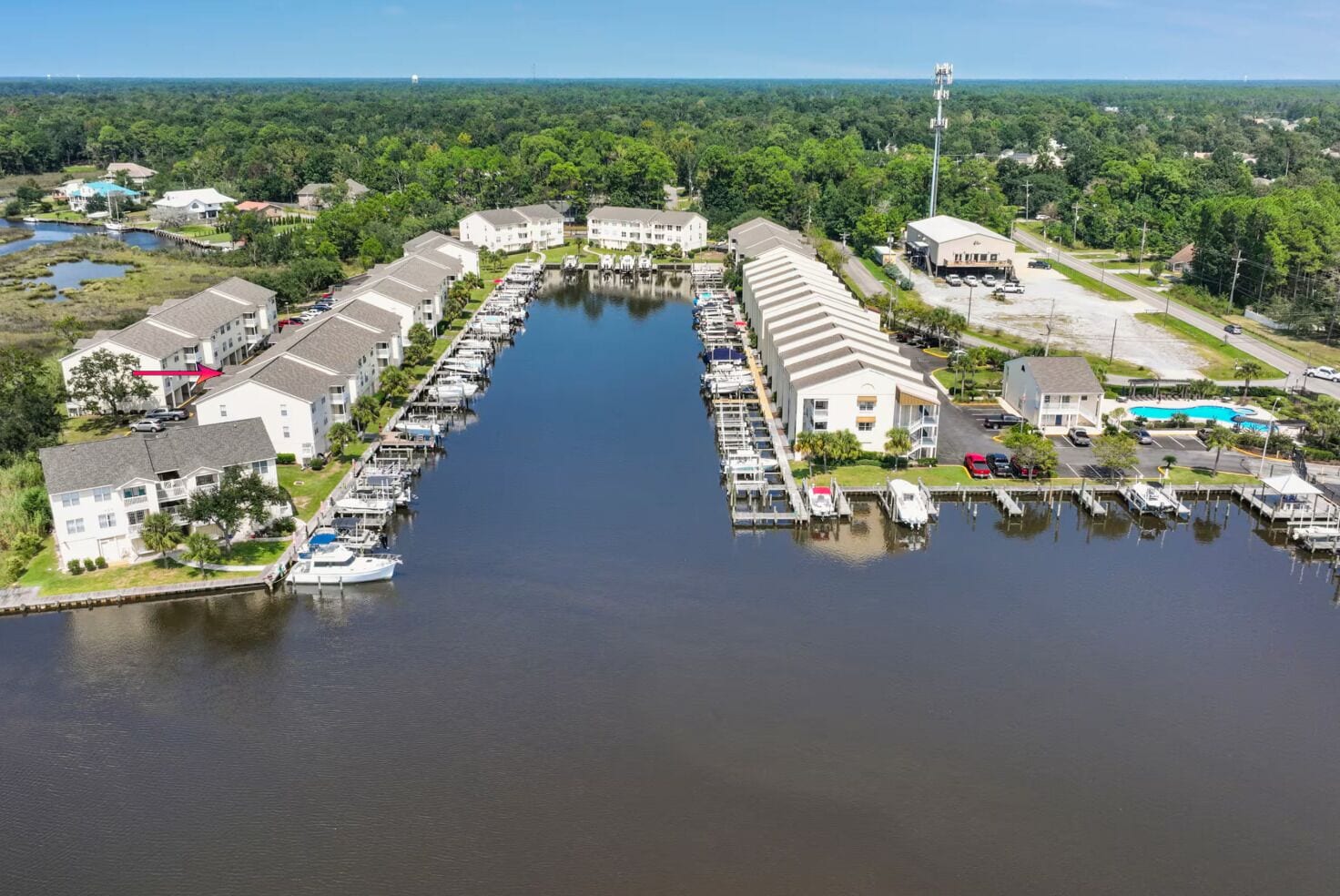 A marina with docked boats, connected buildings, and a clear view of the surrounding forest.