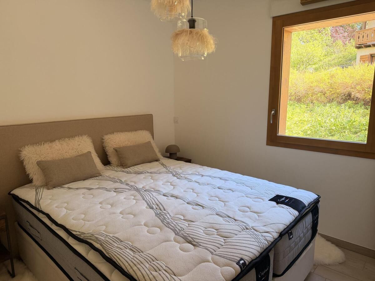 A bed with a white quilt, two pillows, and a wooden headboard.