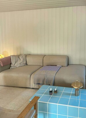 Ein Zimmer mit einer Couch, einem Tisch mit Kerzen und einer Lampe.