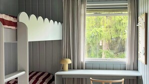 Quarto com uma cama de solteiro, uma escrivaninha e uma cadeira.