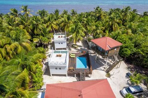 A beachfront property with multiple buildings, a swimming pool, and a red-roofed structure. - North Beach Retreat  (San Pedro)