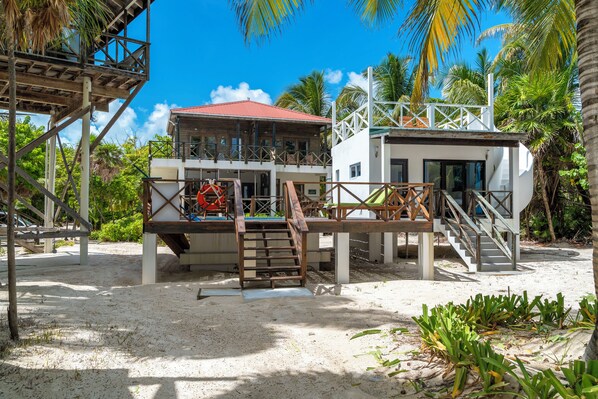A beachfront property with a wooden deck, a lifeguard tower, and a white building with a red roof.