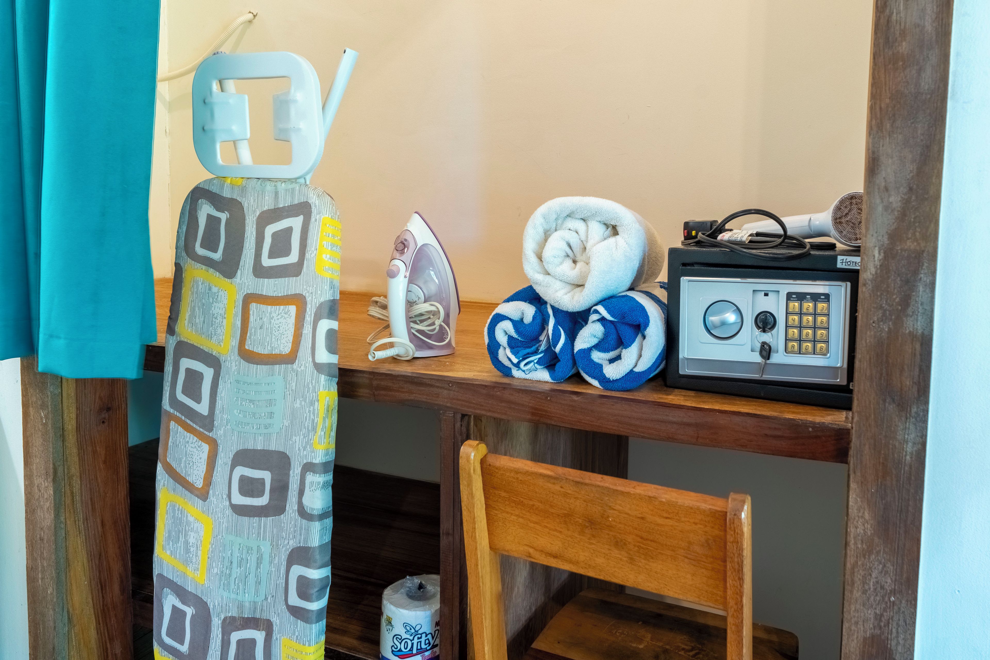 A bathroom with a wooden chair, a towel, an iron, and a radio on a wooden shelf.