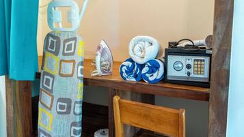 A bathroom with a wooden chair, a towel, an iron, and a radio on a wooden shelf.
