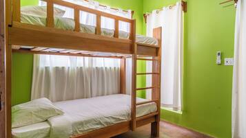 A bunk bed room with a ladder, a window with curtains, and a power outlet on the wall.