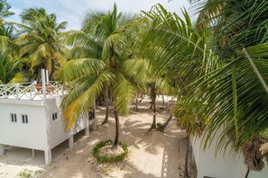 A resort with multiple palm trees, a white building with a balcony, and a sandy ground. - North Beach Retreat  (San Pedro)