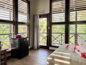 A room with a bed, a desk, a refrigerator, and a window with blinds. - North Beach Retreat Belize (San Pedro)