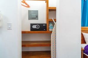 A room with a bed, a wooden shelf, a radio, and a light switch.