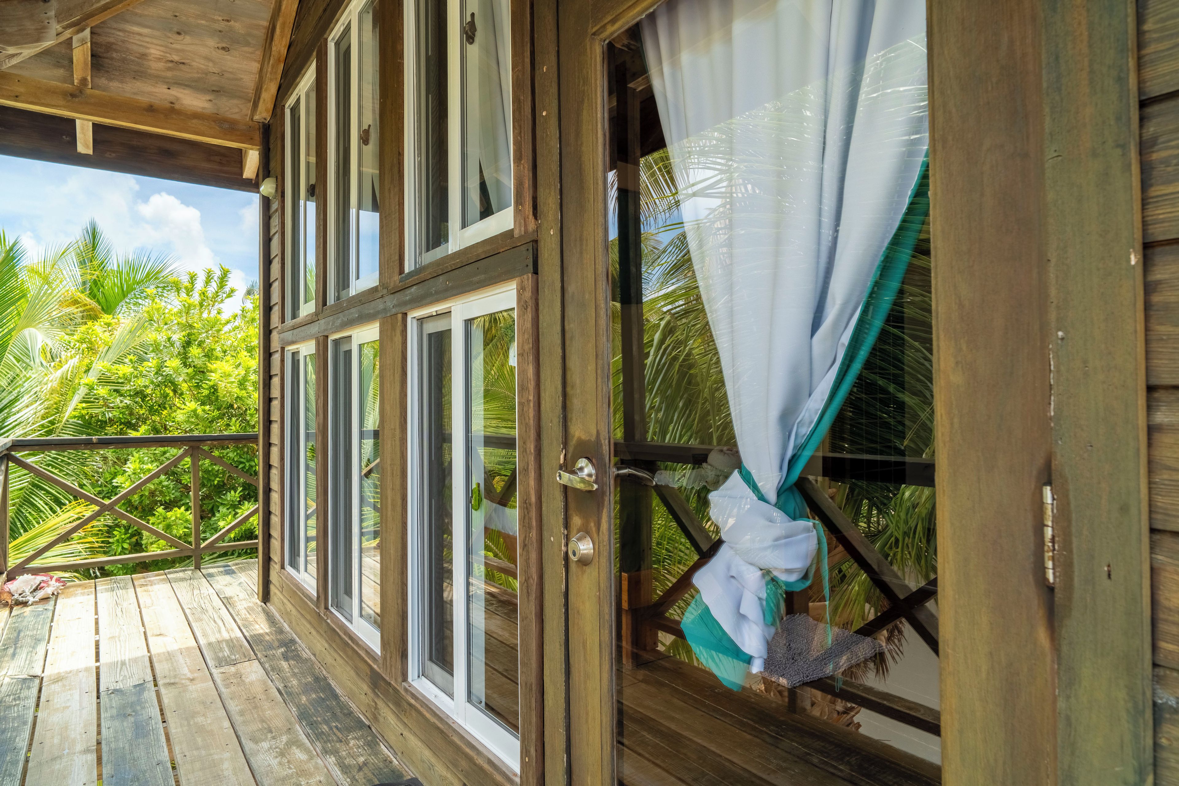 Un balcon en bois offrant une vue sur la végétation tropicale.