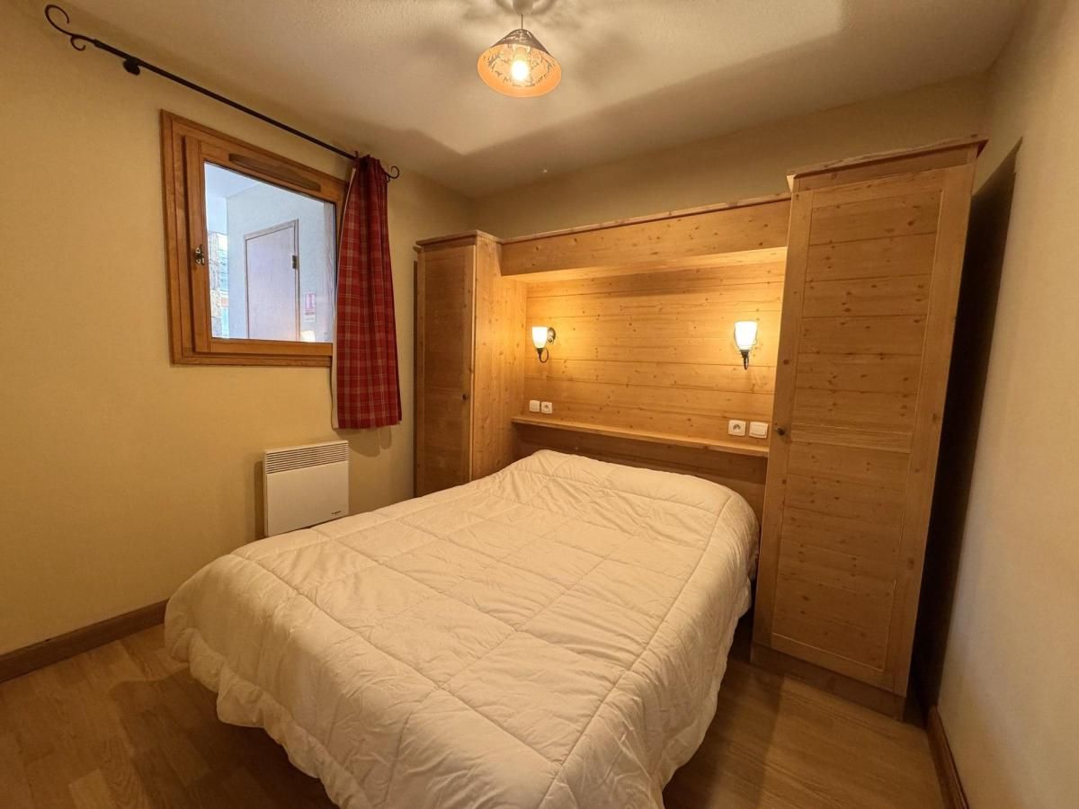 A bedroom with a bed, a window, a radiator, and wooden walls.