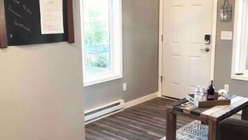 Une pièce avec un plancher en bois, une porte, une fenêtre et un panneau fixé au mur.