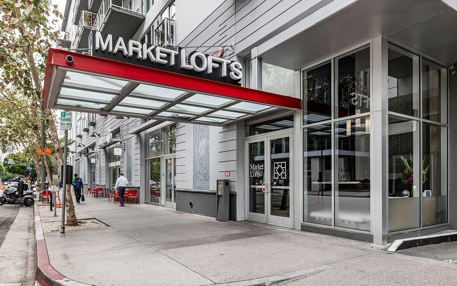 En byggnad med en butiksfasad där det står ”MARKET LOFTS” och en ingång med ett överhäng.