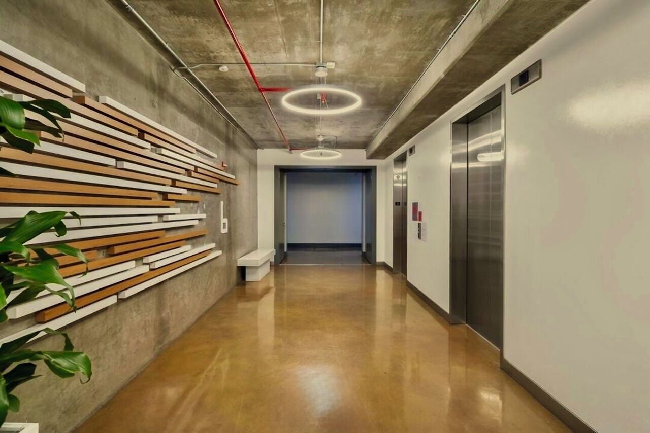 A modern hallway with a wooden slat wall, a polished floor, and an elevator.