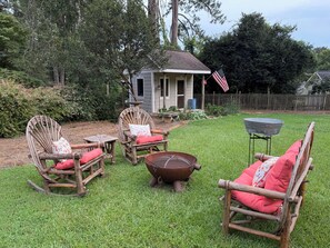 Ein Garten mit einem kleinen Haus, einer Feuerstelle und Gartenmöbeln.