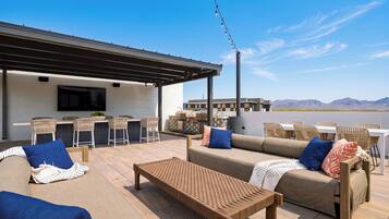 Une terrasse extérieure aménagée avec un canapé, des chaises, une table et un espace barbecue.