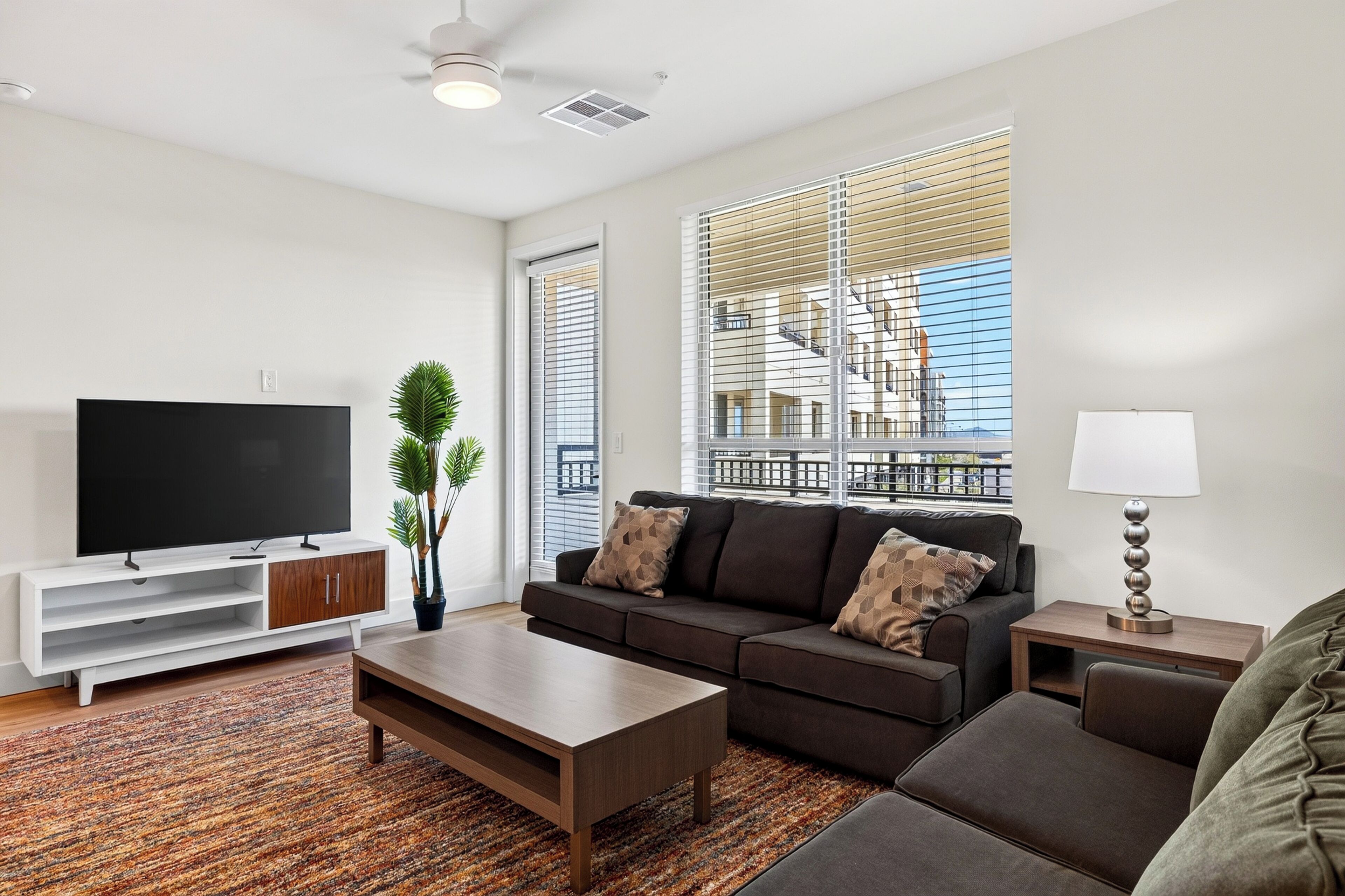 A modern living room with a flat-screen TV, a sofa, a coffee table, and a lamp.