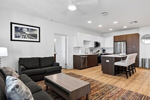 A modern apartment with a living room, kitchenette, and dining area.