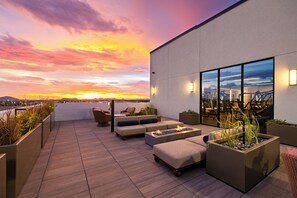 Terraza en la azotea con asientos, una chimenea y vistas al atardecer sobre la ciudad.
