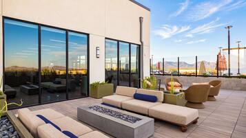 A modern outdoor seating area with a fire pit, sofas, and chairs, overlooking a desert landscape.