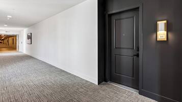 Un couloir avec une porte sombre, un interrupteur et une plaque d’immatriculation.