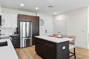 A modern kitchen with a central island, stainless steel appliances, and wooden cabinetry.