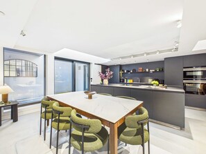 A modern kitchen with a central island, a dining area with a marble table, and a view through a large window. - Spacious London Bridge Townhouse with Roof Terrace (Greater London)