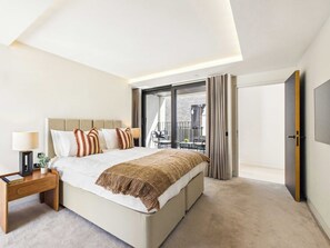 A modern bedroom with a large bed, bedside table, and a view of the outside balcony. - Spacious London Bridge Townhouse with Roof Terrace (Greater London)